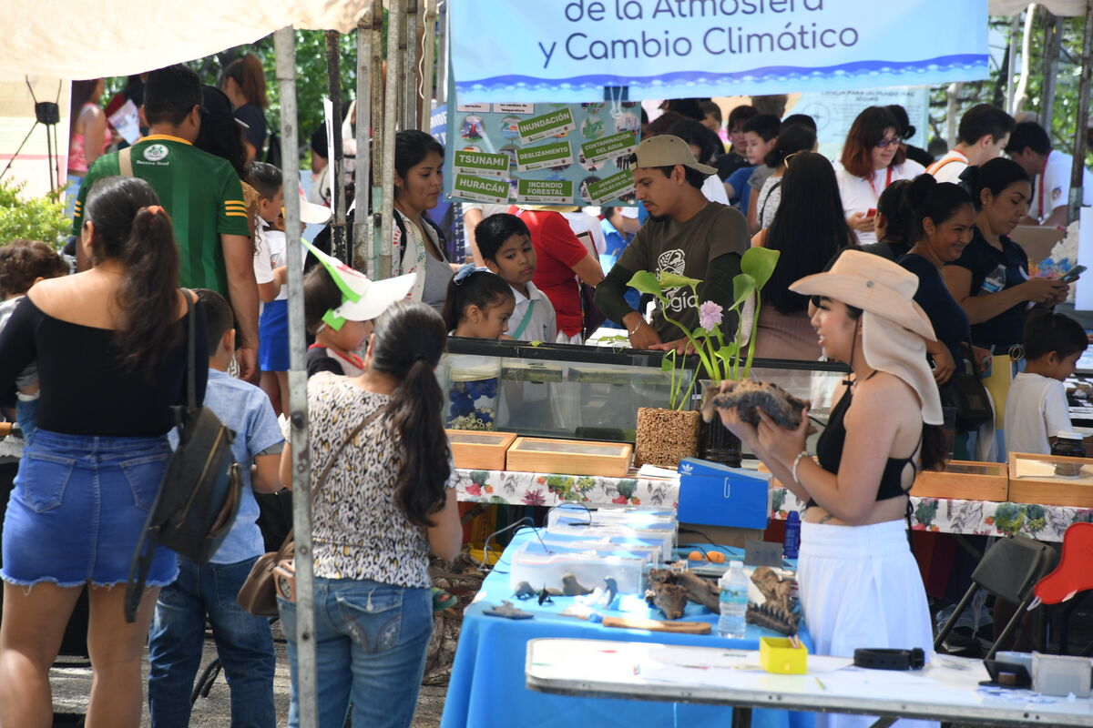 Talleristas atendiendo a visitantes bajo las carpas